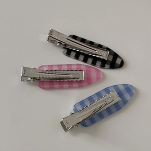 Detailed view of classic plaid hair clips with acrylic texture and silver metal grip
