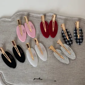 Detail view of 12 piece acetate hair clip set with gold metal duckbill clips on felt