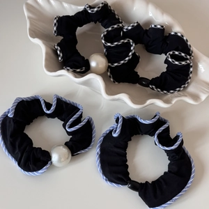 Détail de chouchous noirs avec perles élégantes et motifs rayés dans un plat en céramique