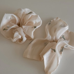 Détail du chouchou en mousseline abricot avec broderies florales et rubans élégants