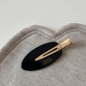 Detailed macro view of black oval acetate hair clip with gold France Handmade logo
