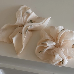 Vue détaillée de broderies florales sur des chouchous en mousseline beige doux