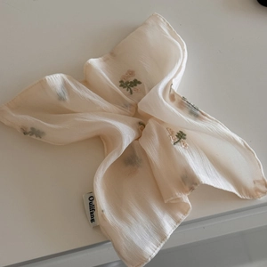 Détail d'un chouchou en tissu beige avec de petites fleurs roses brodées délicates