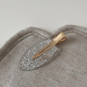 Detail showing silver glitter acetate oval clip with a polished gold metal hair grip