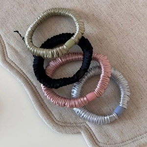 Lot de quatre chouchous en satin champagne, noir, rose et gris avec texture plissée