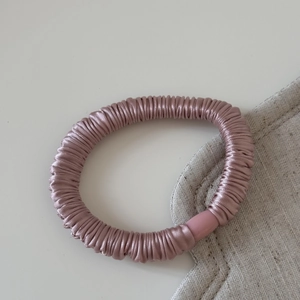 Détail du chouchou rose en soie avec texture plissée et élastique à cheveux sans couture