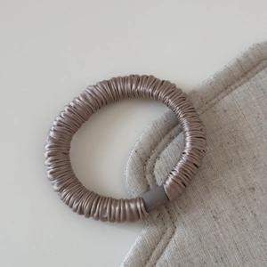 Détail du chouchou sans couture en soie dorée avec boucle cylindrique gris mat élégante