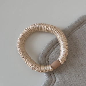 Vue détaillée d'un chouchou en satin champagne avec une texture plissée élégante
