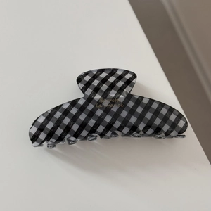Detail view of checkered pattern and gold text on a French style shark hair claw clip