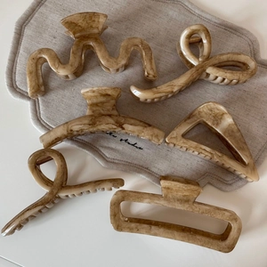 Close-up of set of six marble patterned resin hair claws in various geometric shapes