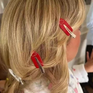 Detail view of red and white acetate hair clips with heart patterns on blonde hair