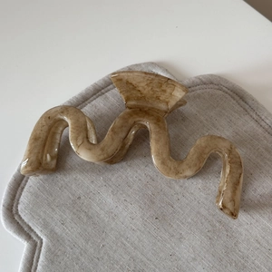 Detailed view of large apricot marble hair claw clip on soft textured fabric surface
