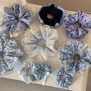 Close-up of blue scrunchies set with plaid, floral patterns and lace details