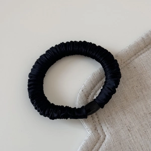 Détail d'un chouchou en soie noire avec plis fins et perle en résine élégante