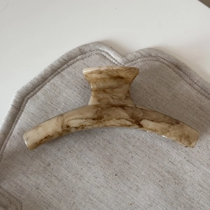 Close-up of beige marble pattern claw clip on textured fabric background