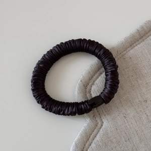 Gros plan d'un chouchou en soie noire sans couture avec texture plissée et attache