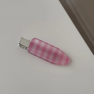 Detail of pink gingham pattern hair clip with silver metal base on white background