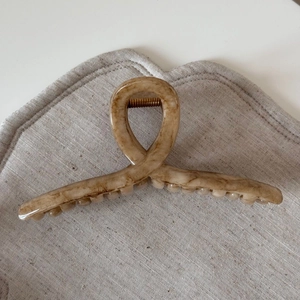 Close-up of beige marble hair claw clip with acetate texture and strong metal spring