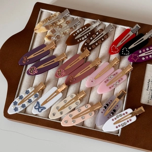 Detailed close-up of marble pattern hair clips with rhinestones in a velvet tray