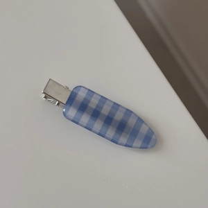 Detail view of a vintage blue and white checkered claw clip with a sleek metal clasp