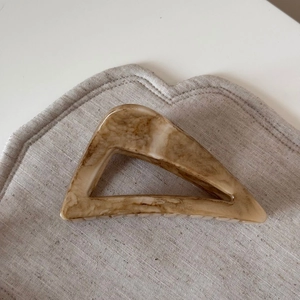 Detailed macro view of apricot marble pattern hair claw clip on beige linen background