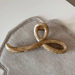 Macro shot of apricot marble large hair claw clip with golden spring on linen cloth