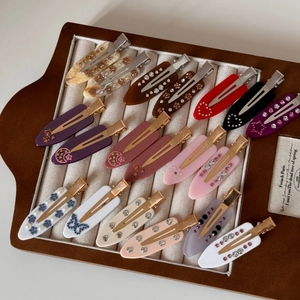 French marble acetate hair clips with rhinestones and pearls on a brown leather tray