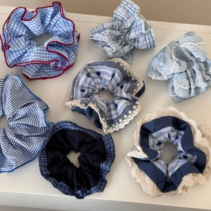 Detail of seven blue and white patterned scrunchies with floral embroidery and lace trim