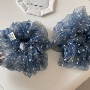 Vue détaillée de deux chouchous faits main en organza bleu nuit à pois sur surface blanche