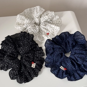 Detailed view of three polka dot scrunchies with handmade tags and red heart beads