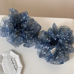 Gros plan de chouchous faits main en organza bleu marine à pois sur surface blanche
