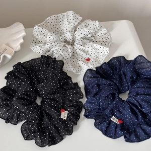 Detailed view of three polka dot scrunchies with ruffles, handmade labels and bead accents