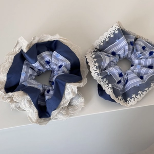 Detailed close-up of blue plaid scrunchies with white lace edges and soft pompom accents