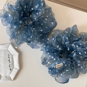 Détail de chouchous en organza bleu marine à fleurs blanches avec étiquette fait main