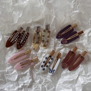 Detailed close-up of French acetate hair clips with marble patterns and inlaid rhinestones