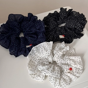 Detailed view of large polka dot scrunchies in navy, black, and white with handmade labels
