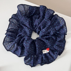Detail of navy blue polka dot scrunchie with handmade label and red heart button decor