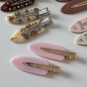 Detail showing various marble pattern acetate duckbill clips with rhinestone inlay