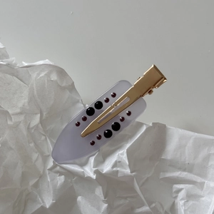Macro shot of marble texture french acetate hair clip with gold metal duckbill clip design