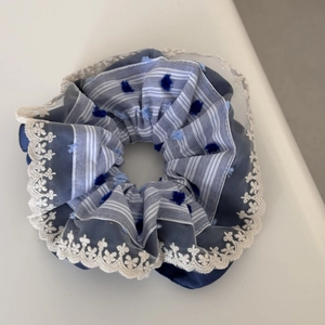 Blue and white striped scrunchie with navy pom-poms and white lace floral trim detailing