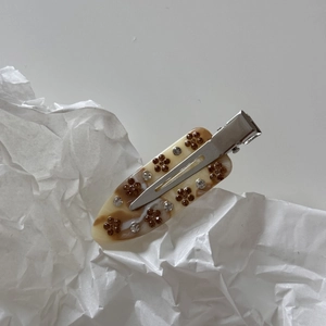 Detail of marble pattern acetate hair clip with floral accents and sparkling rhinestones