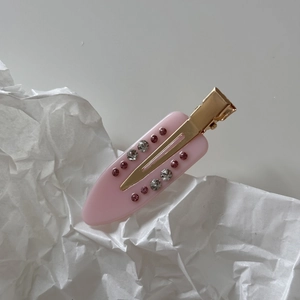 Macro detail of French marble pink acetate hair clip with rhinestones and gold metal base