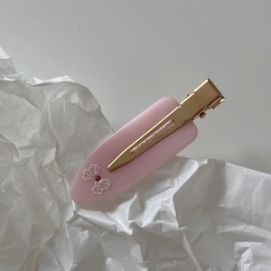 Close-up of pink acetate hair clip with pearl bow design and gold metal base detail