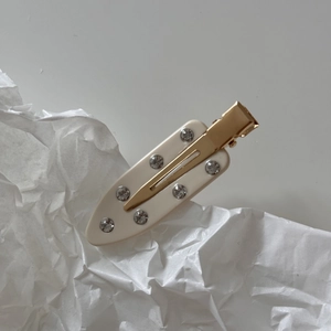 Close-up of cream marble acetate hair clip with eight embedded sparkling rhinestones