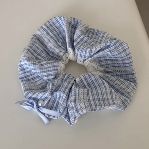 Detail of blue plaid scrunchie with white lace edges and a faux pearl ribbon bow