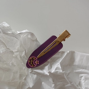 Close-up of purple acetate hair clip with gold metal duckbill clip and moon star patterns