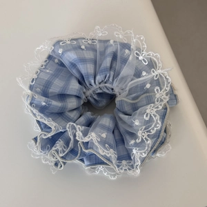 Detail view of blue plaid scrunchie with delicate white lace edging and floral embroidery
