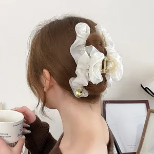 Détail d'une pince à cheveux en satin blanc crème avec pendentif cœur doré sur cheveux