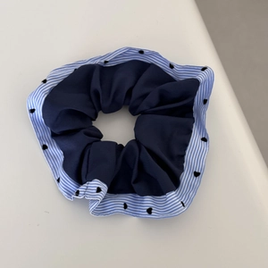 Detailed shot of navy blue scrunchie with striped edges and black heart pattern