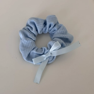 Detail of light blue scrunchie with rib knit texture and elegant satin bow
